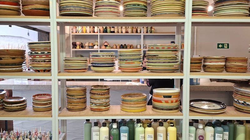 Estante com cerâmicas prontas e produtos para a pintura da peça - Alessandra Taraborelli