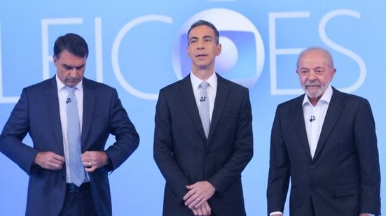Lula e Flávio Bolsonaro ladeiam César Tralli antes do início do debate de sexta-feira, na Globo - Carlos Elias Junior/Agência O Dia/Estadão Conteúdo