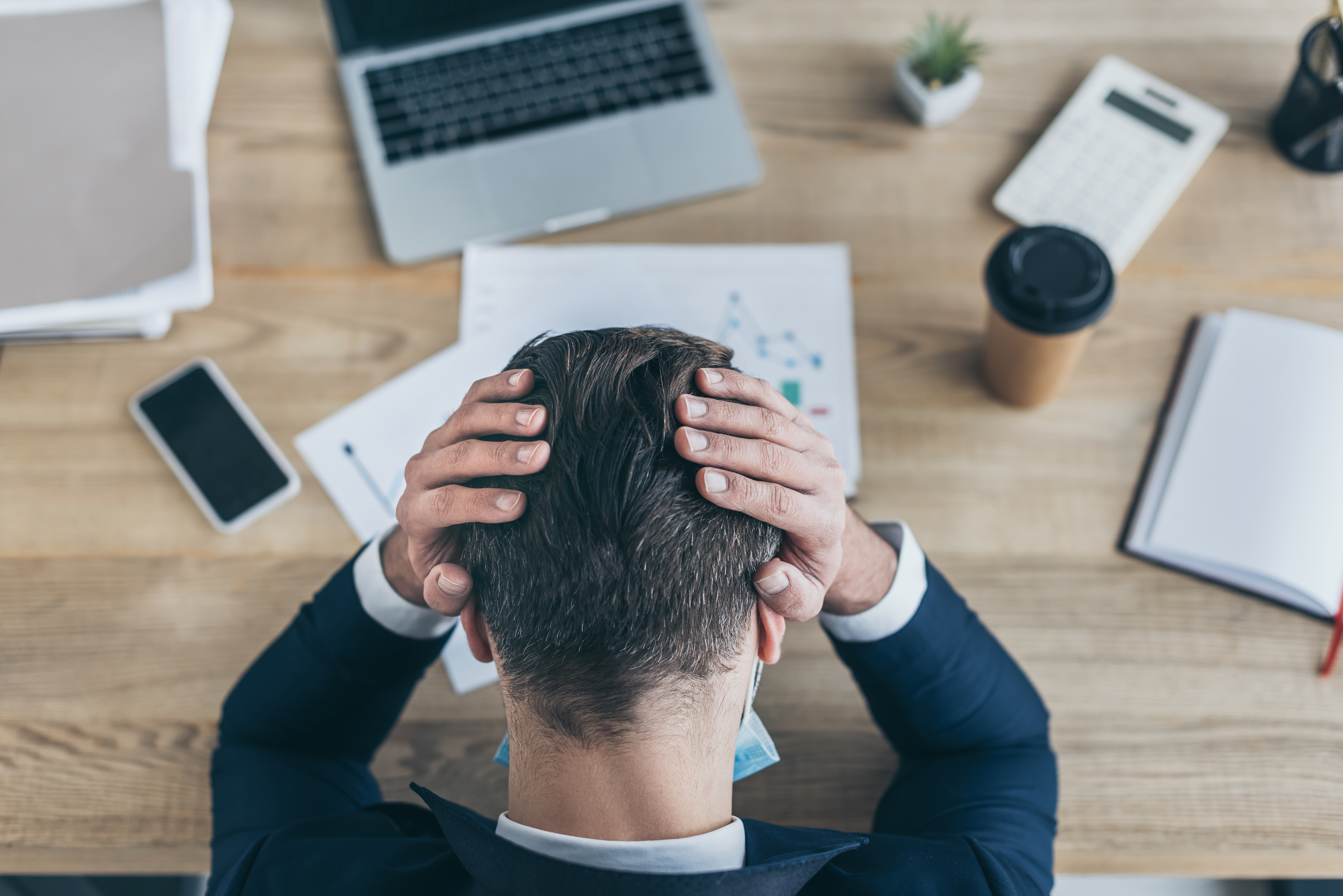 homem com as mãos na cabeça na mesa de trabalho