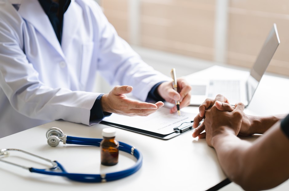 Médico e paciente em uma mesa com papéis e fichas de diagóstico