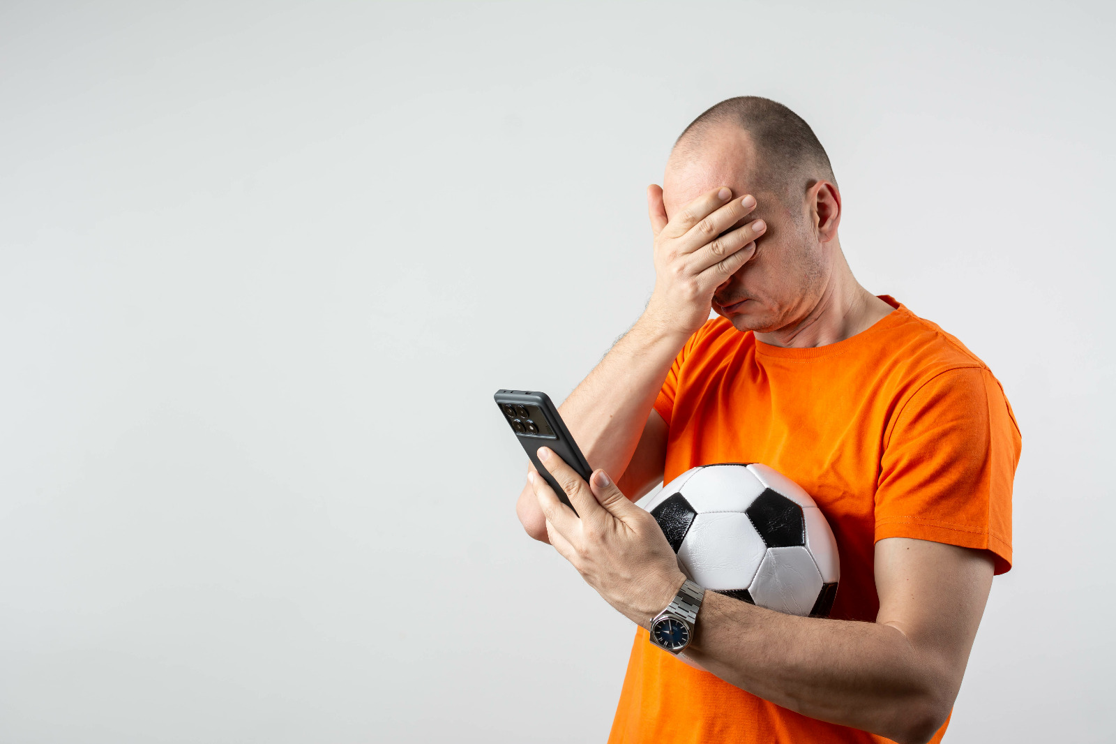 Homem com celular e bola na mão