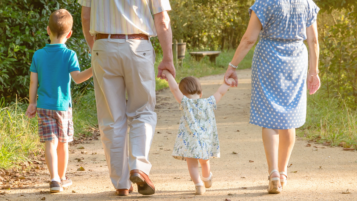 dois avós segurando as mãos dos netos em um passeio