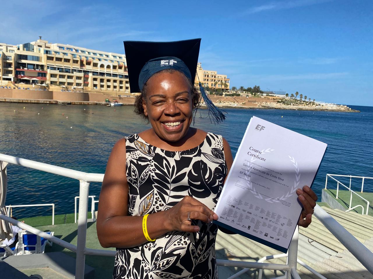 mulher negra com chapéu de formatura e diploma na mão