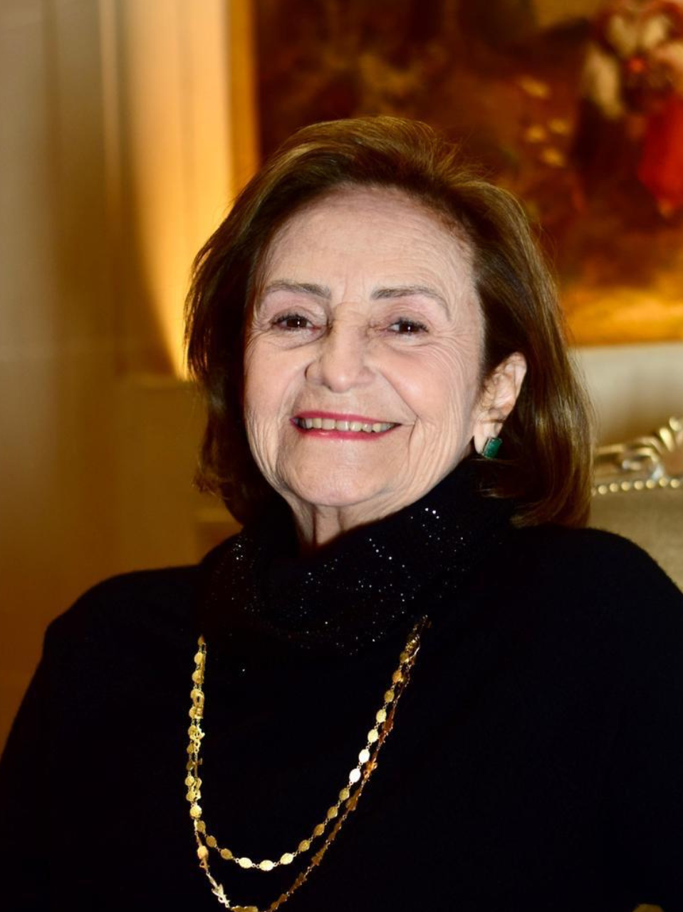 Mãe de Cazuza com cabelos escuros e blusa preta e colar dourado