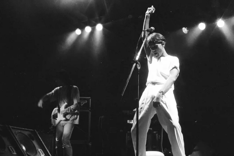 Cazuza em show com camiseta branca, calça e bandana na cabeça 