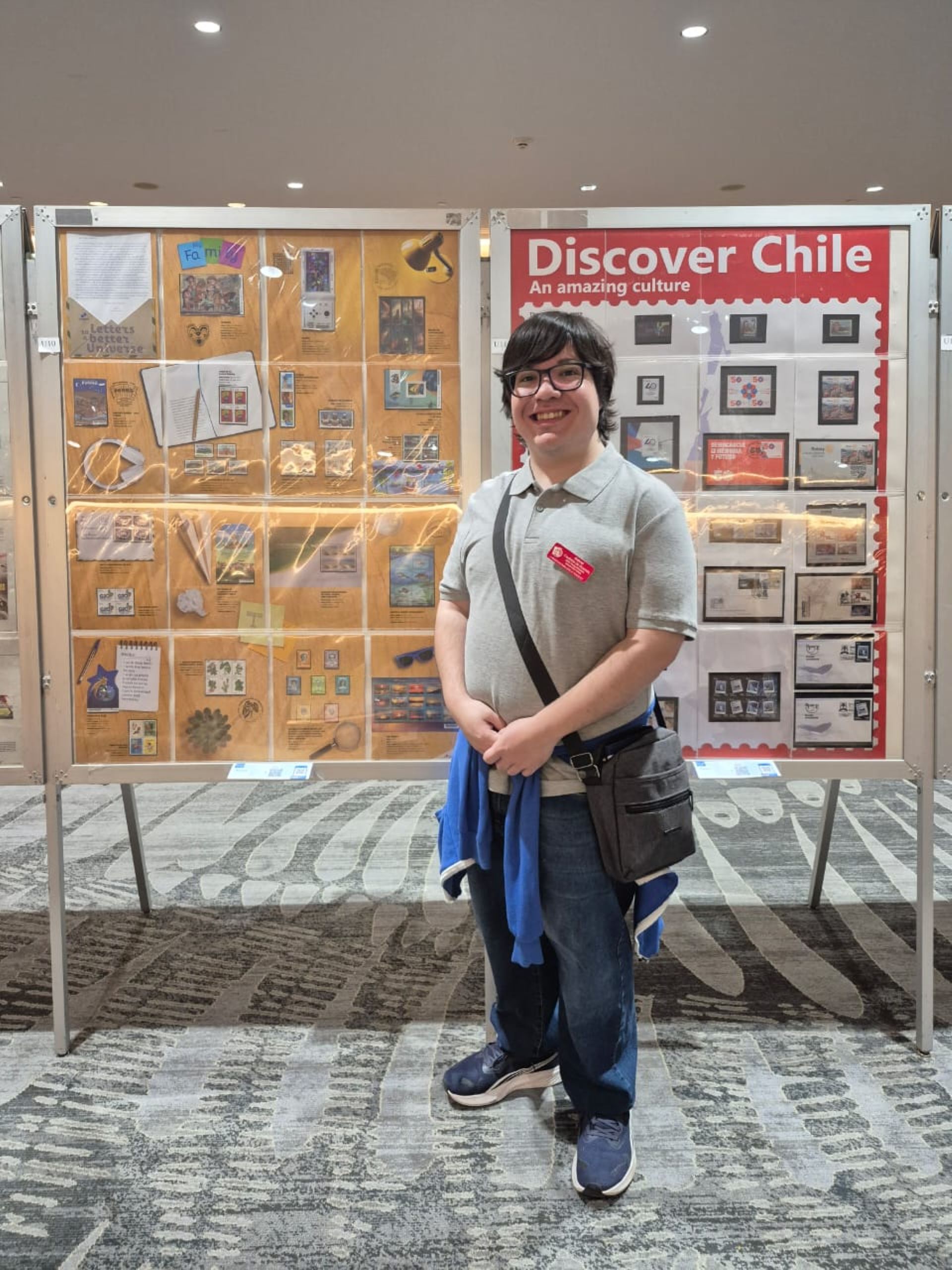 Jovem posando para foto na frente da sua coleção de selos