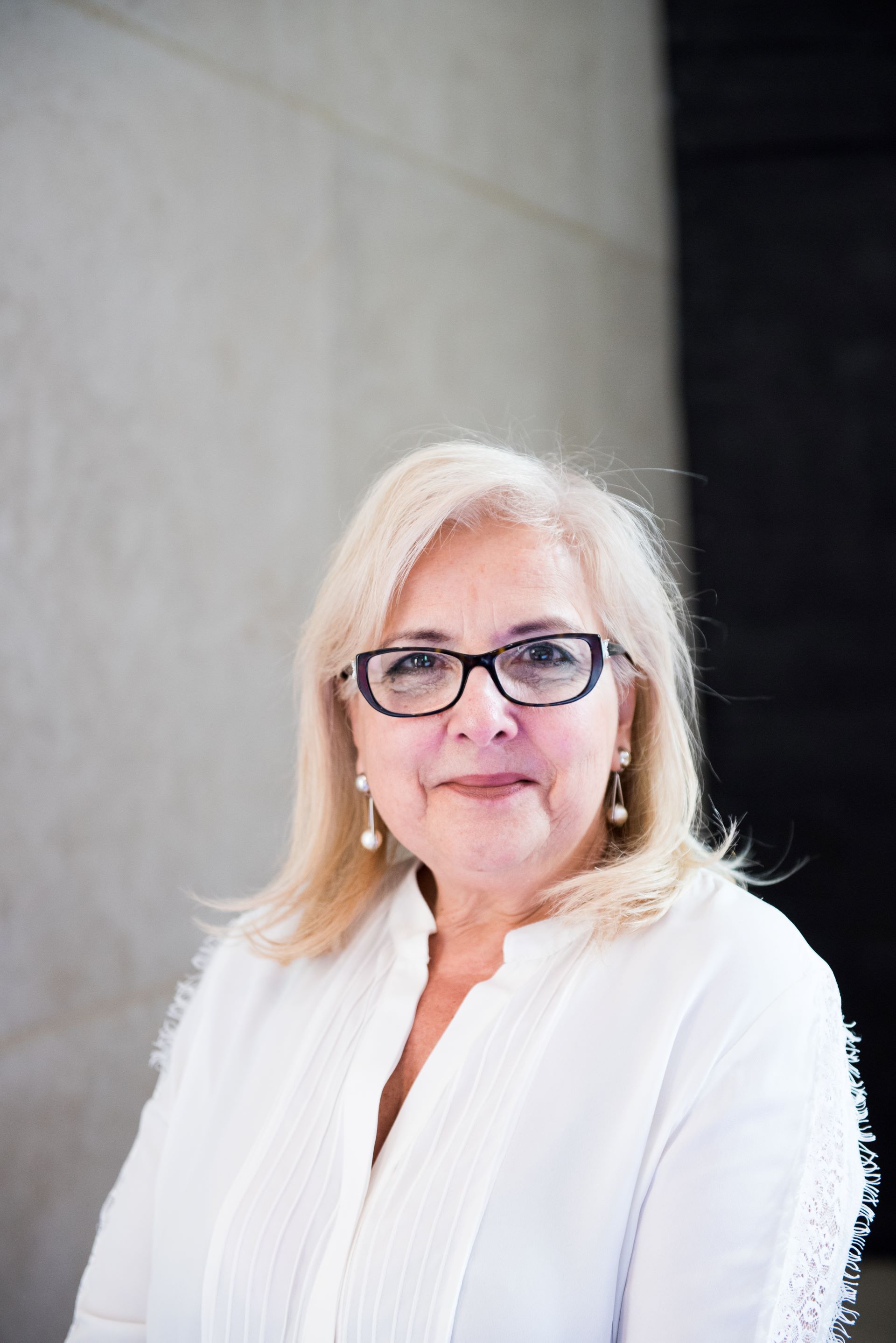 A presidente da ABRH, Leyla Nascimento, posa vestindo blusa branca e óculos de aros escuros