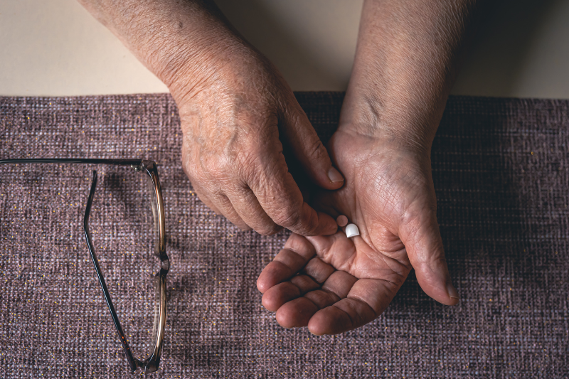 mãos de uma pessoa idosa segurando um comprimido de remédio