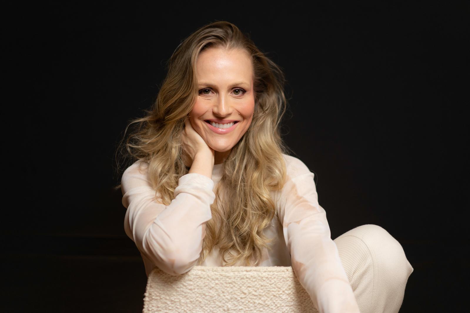 Michelle Schneider sentada descontraidamente e sorrindo para a câmeraso