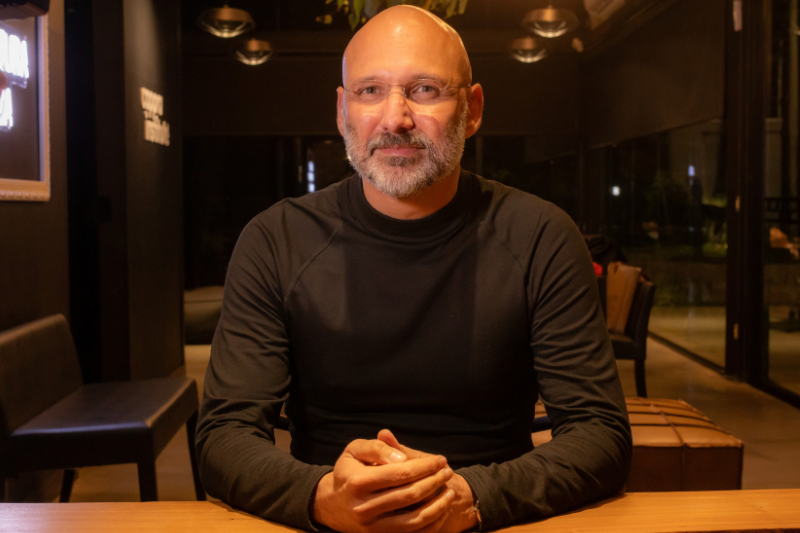 Homem branco de óculos, careca, sentado de frente para a câmera é o ricardo cappra, pesquisador e filósofo 