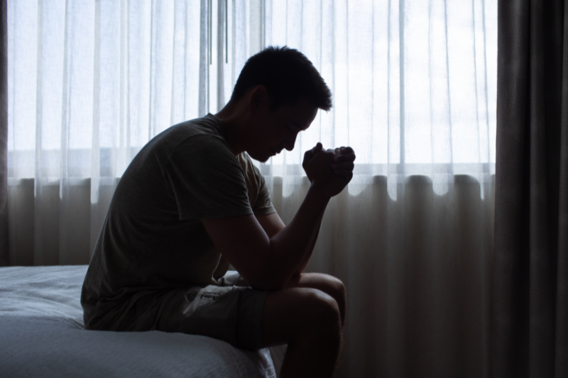 homem sentado na cama e pensativo