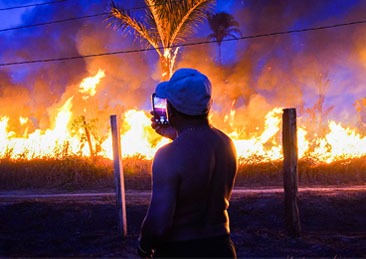 Um homem de pé tira uma foto de uma queimada