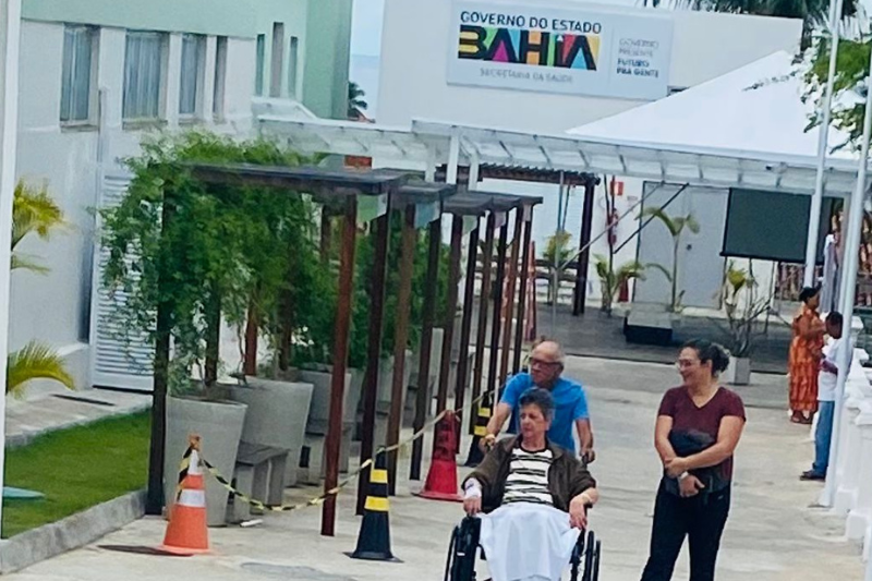 paciente Iaracy passeia de cadeira de rodas com seu marido e sua filha