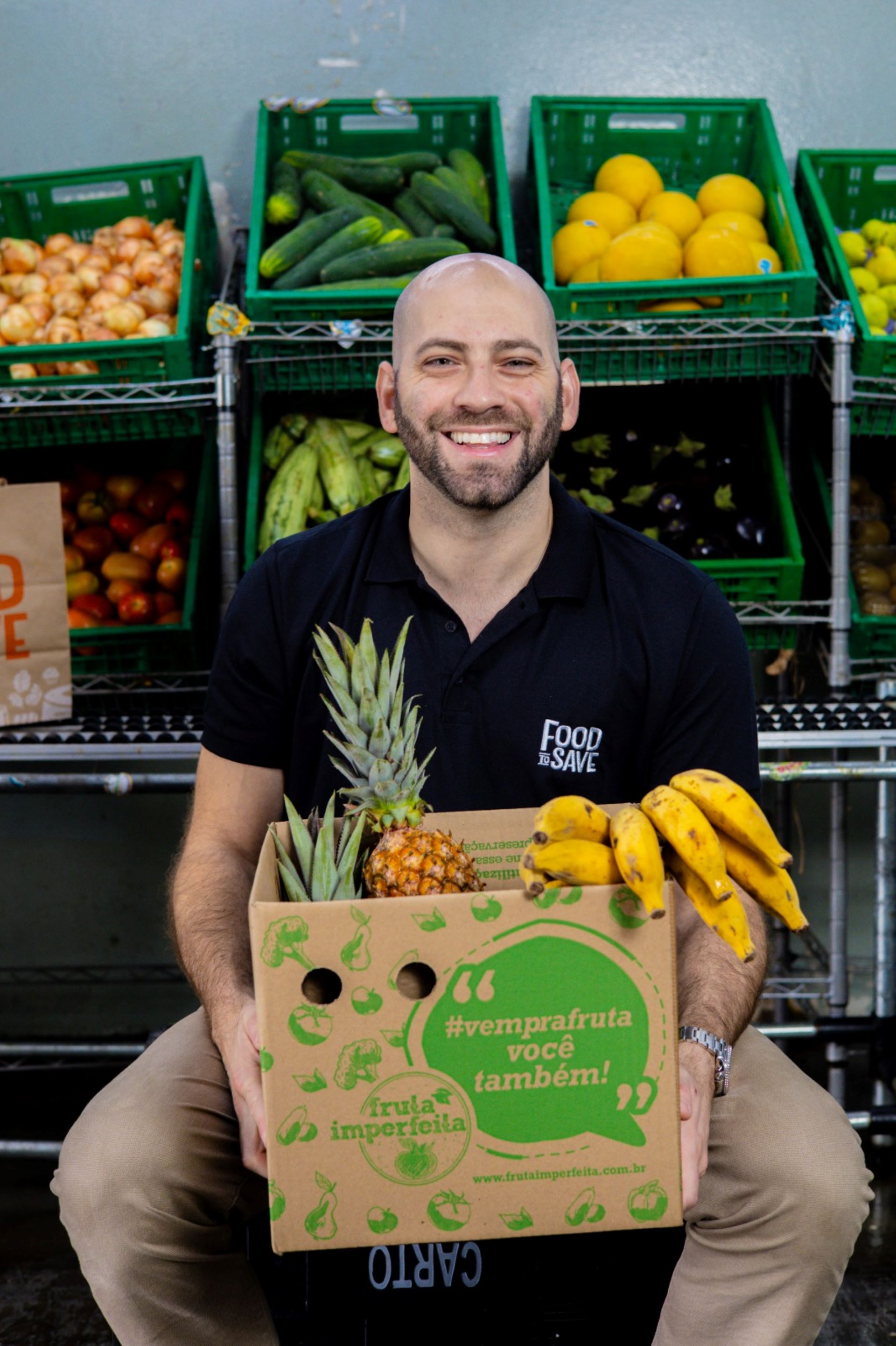 Lucas Infante sentado com uma caixa cheia de frutas
