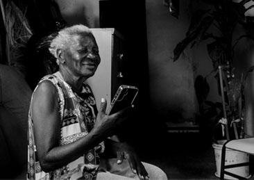 Em preto e branco, uma mulher idosa conversa com sua neta pelo celular