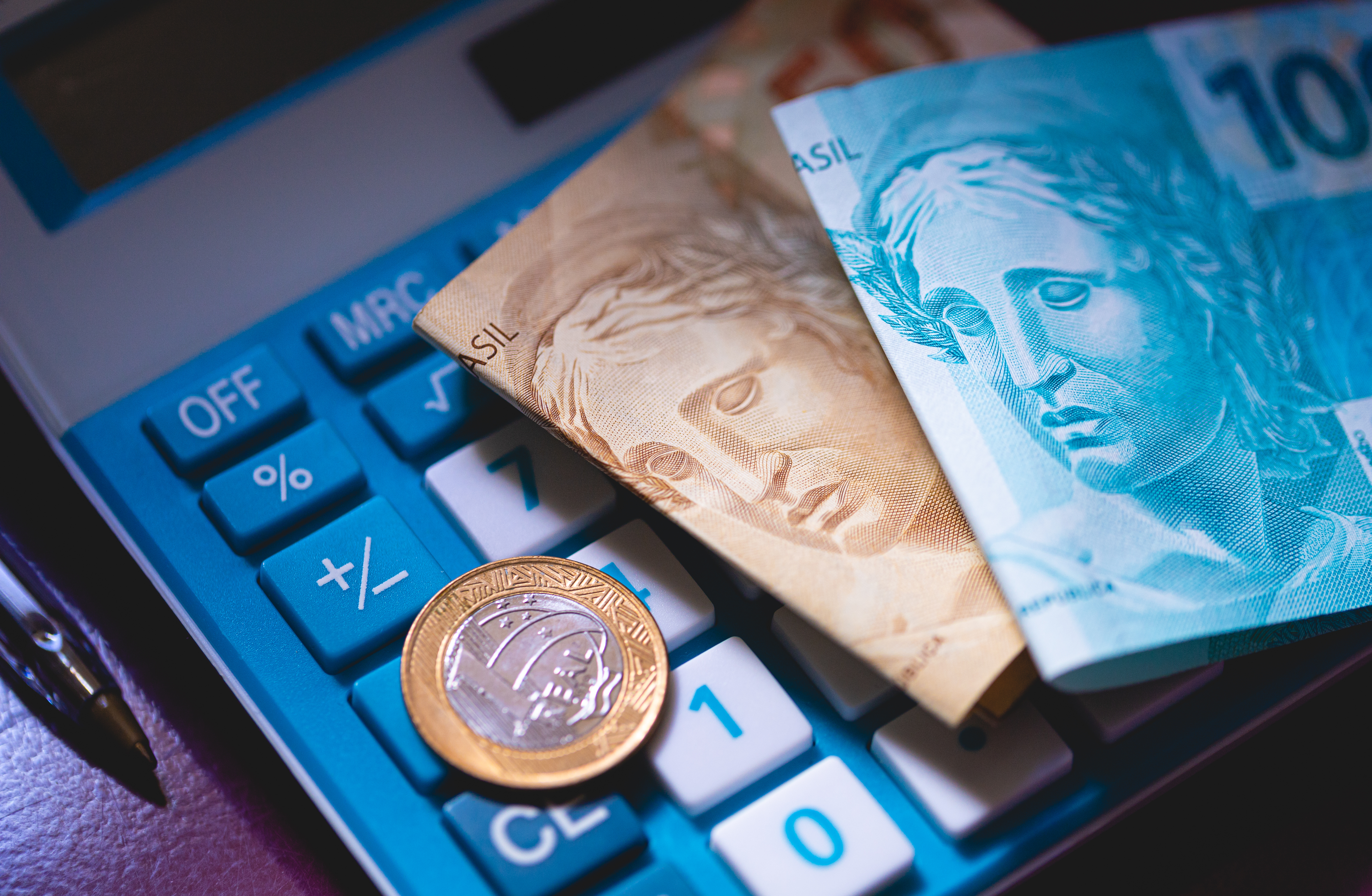 moedas e notas de real e uma calculadora
