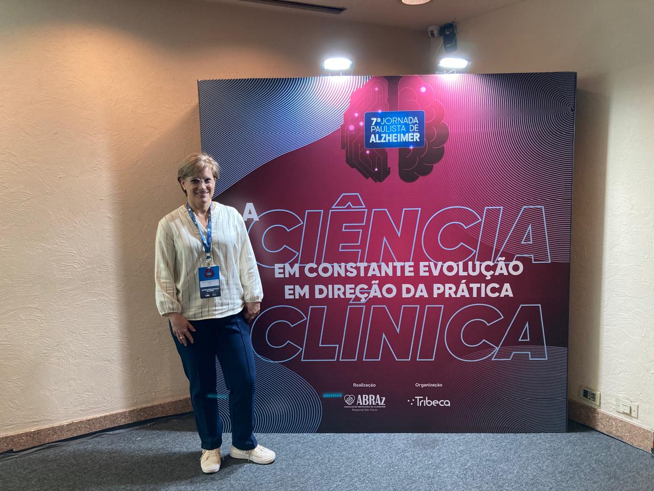 Marcia Cavalheiro em pé em frente a um painel onde se lê ciência