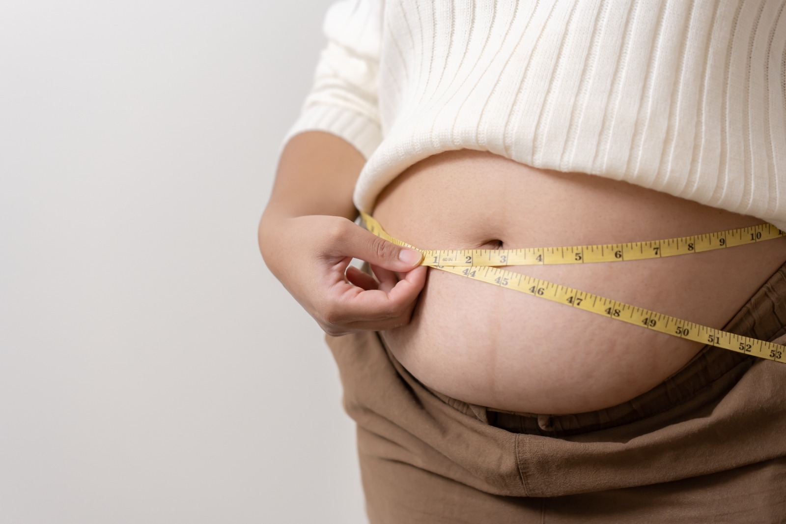 Pessoa mede barriga com fita métrica