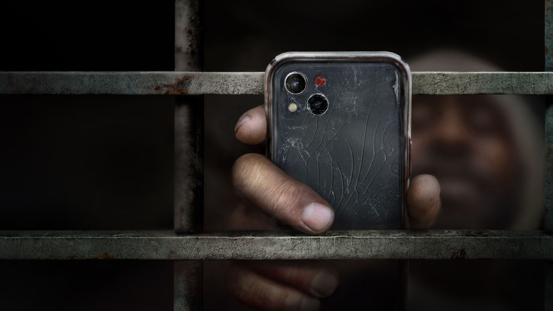 Homem segurando celular quebrado na grade, cena do fimeAlabama: Presos do Sistema