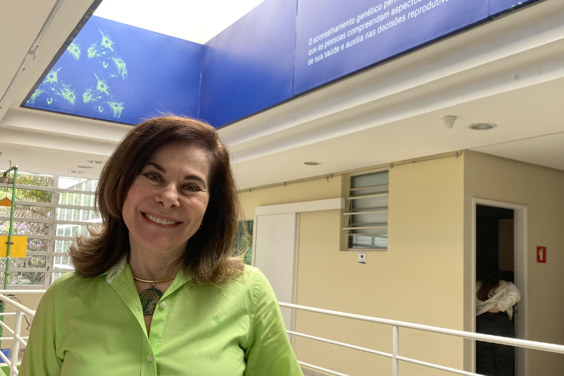 Mayana Zatz é uma mulher idosa, magra, veste uma camisa verde claro, tem cabelos curtos e escuros