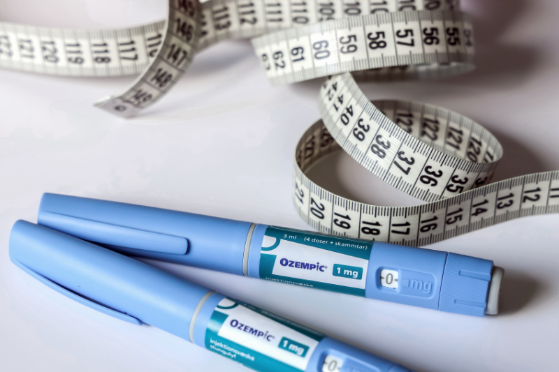 Duas canetas de Ozempic distribuídas em uma mesa ao lado de uma fita métrica
