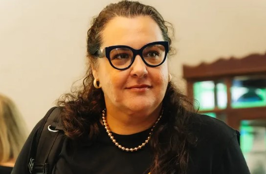 Paula Vialta de óculos e blusa preta, usa um pequeno colar 