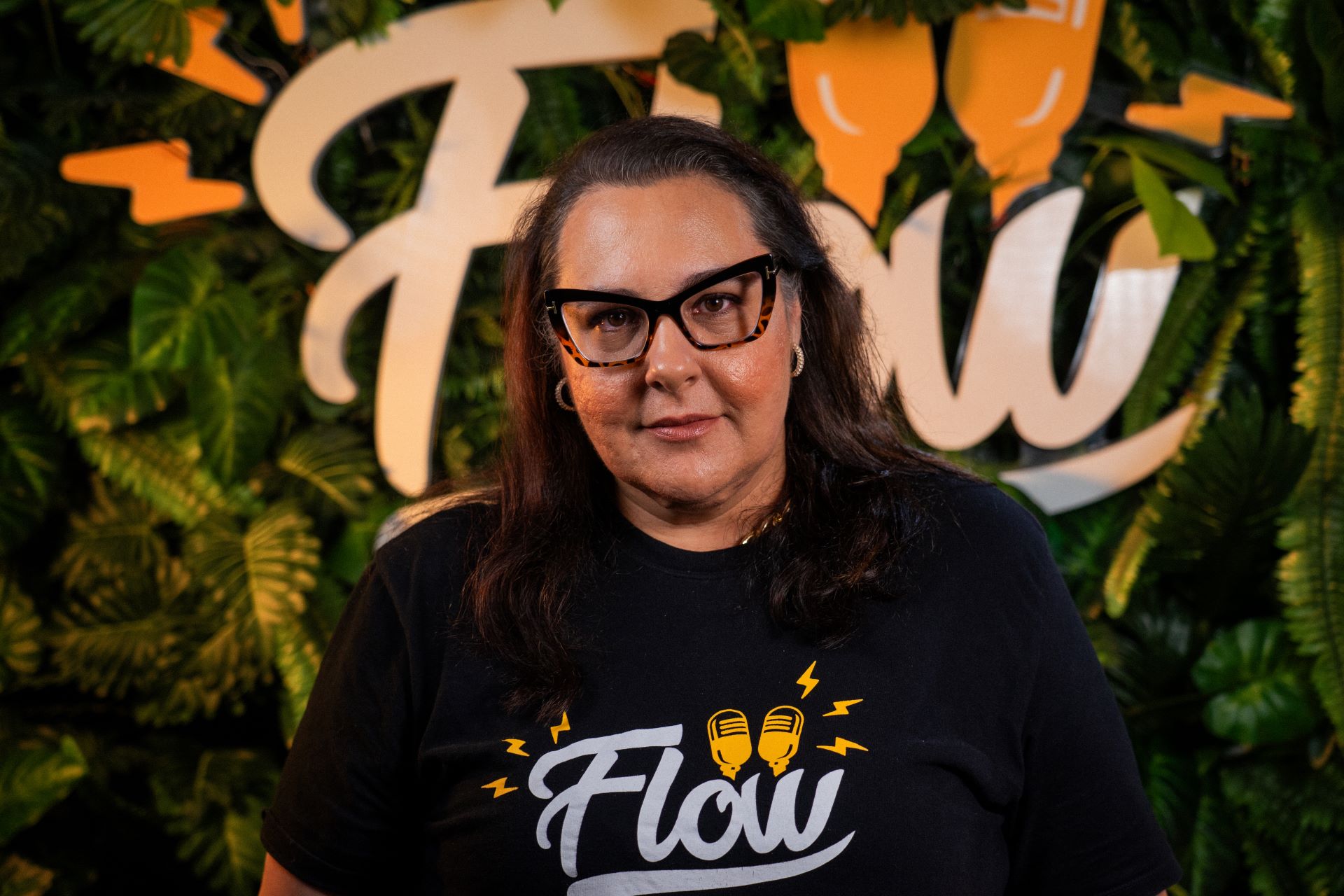 Paula Vialta sorri; usa óculos e camiseta preta onde se lê Flow