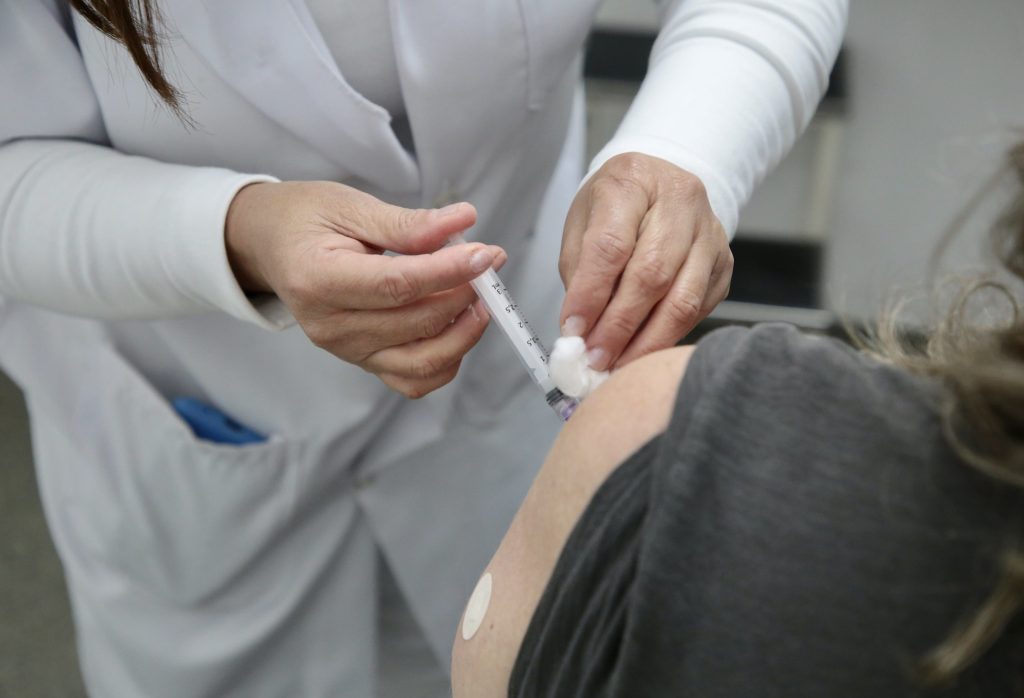 Vacina de sarampo sendo aplicada com destaque para a aplicação e o ante braço do vacinado