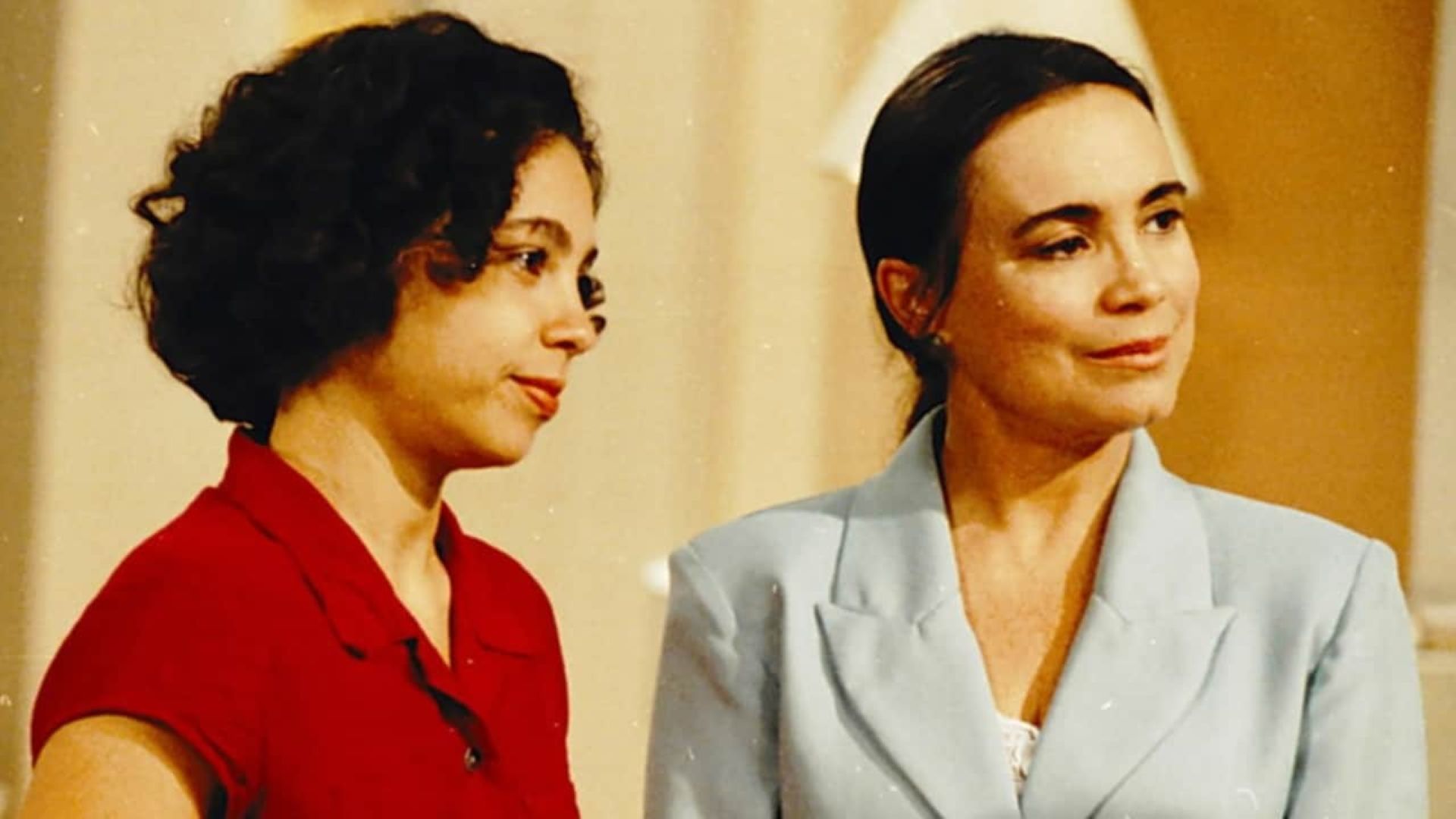 Carla, como Joyce, está de vermelho, ao lado de Regina Duarte,  de terno claro, como Helena