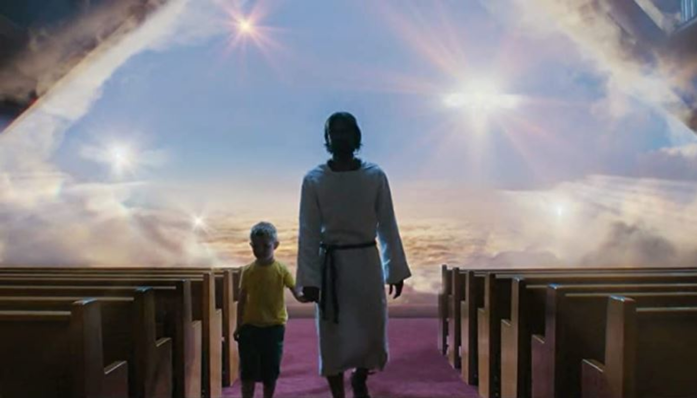 Uma criança está de mãos dadas com uma figura que representa Jesus