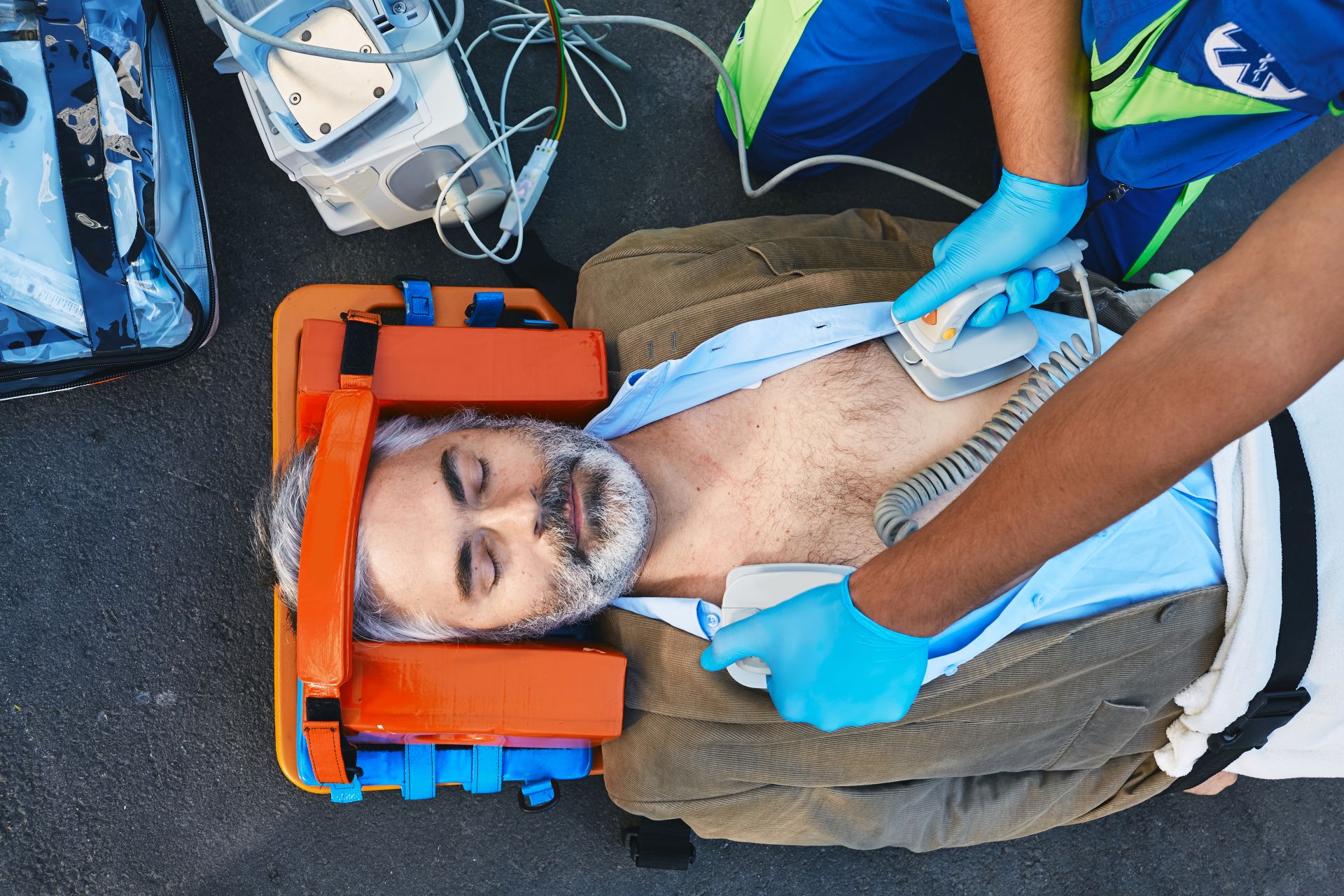 Homem vítima de parada cardíaca em uma maca prestes a receber aplicação de desfibrilador