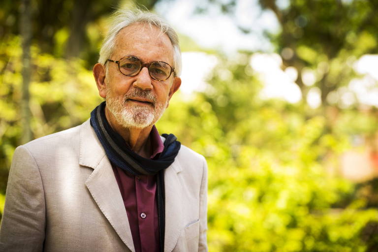 O ator Paulo José está de pé e usa óculos 