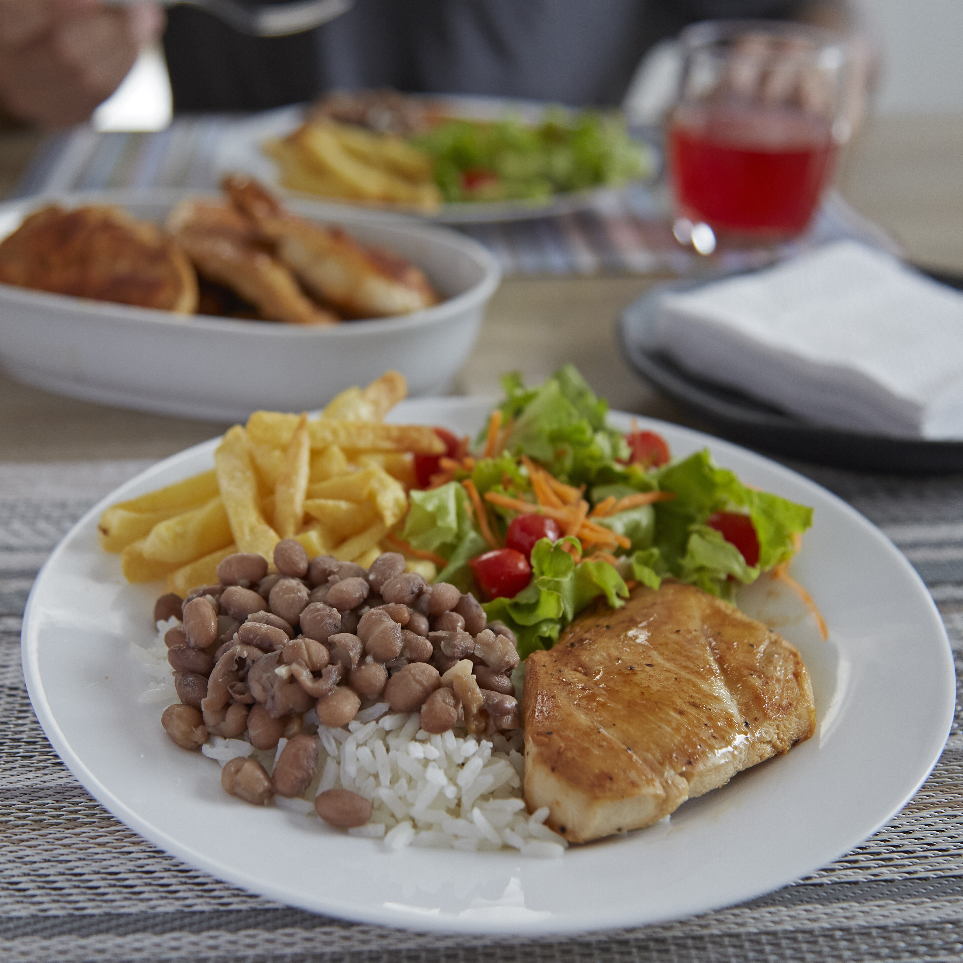 prato de comida com arroz, fejião, filé de frango, batatas fritas e salada