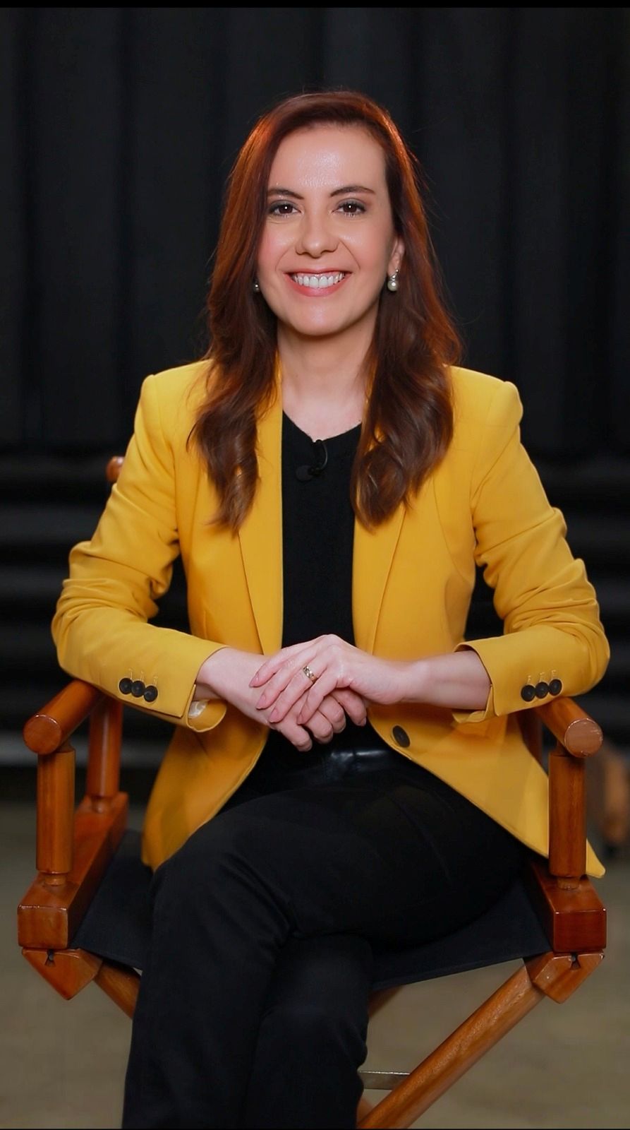 Patricia Lages esta sentada, pernas cruzadas e sorrindo