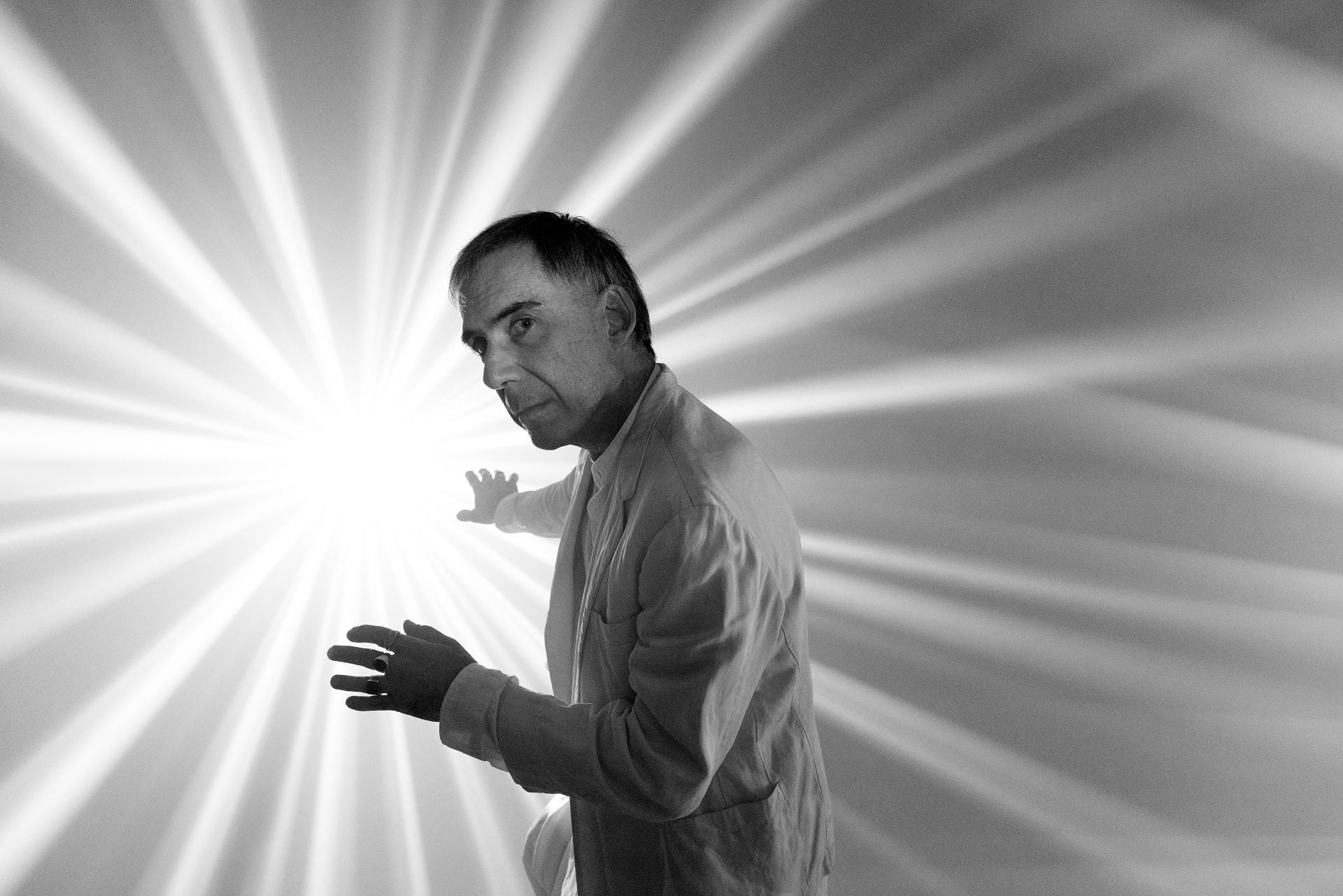 Arnaldo Antunes está na frente de uma luz, em uma foto em preto e branco