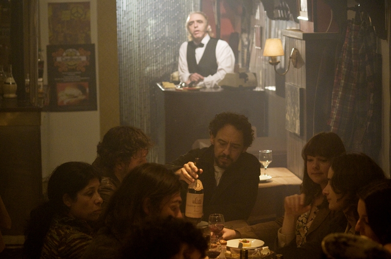 Personagens estão em um bar esfumaçado