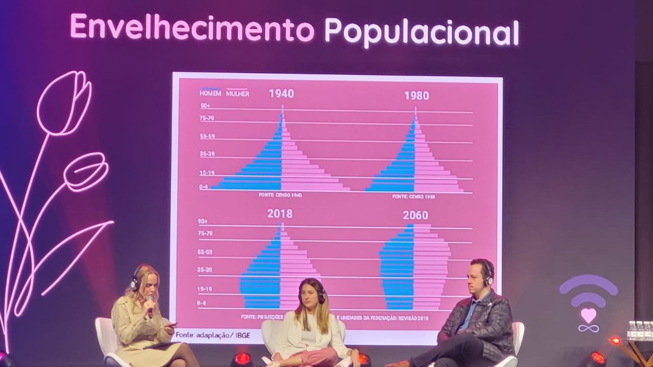 painel com três debatedores sentado em um palco