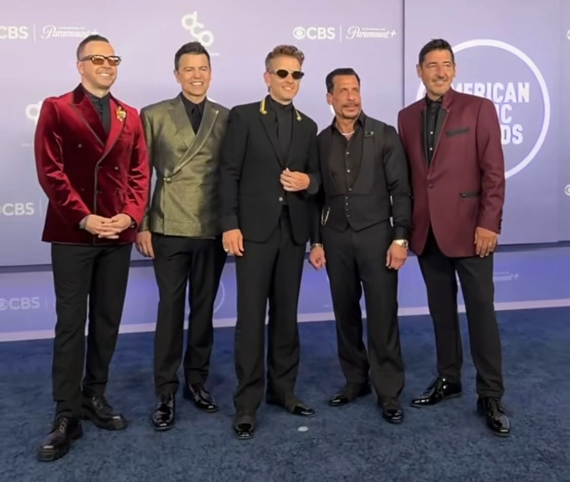 Os cinco integrantes do grupo New Kids On The Block está parado na entrada do local da premiação, posando para fotos