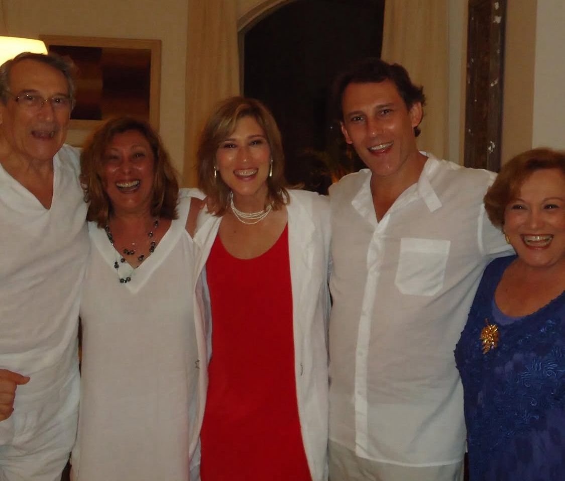 Beth, os irmãos e os pais estão lado a lado, sorrindo e posando para foto