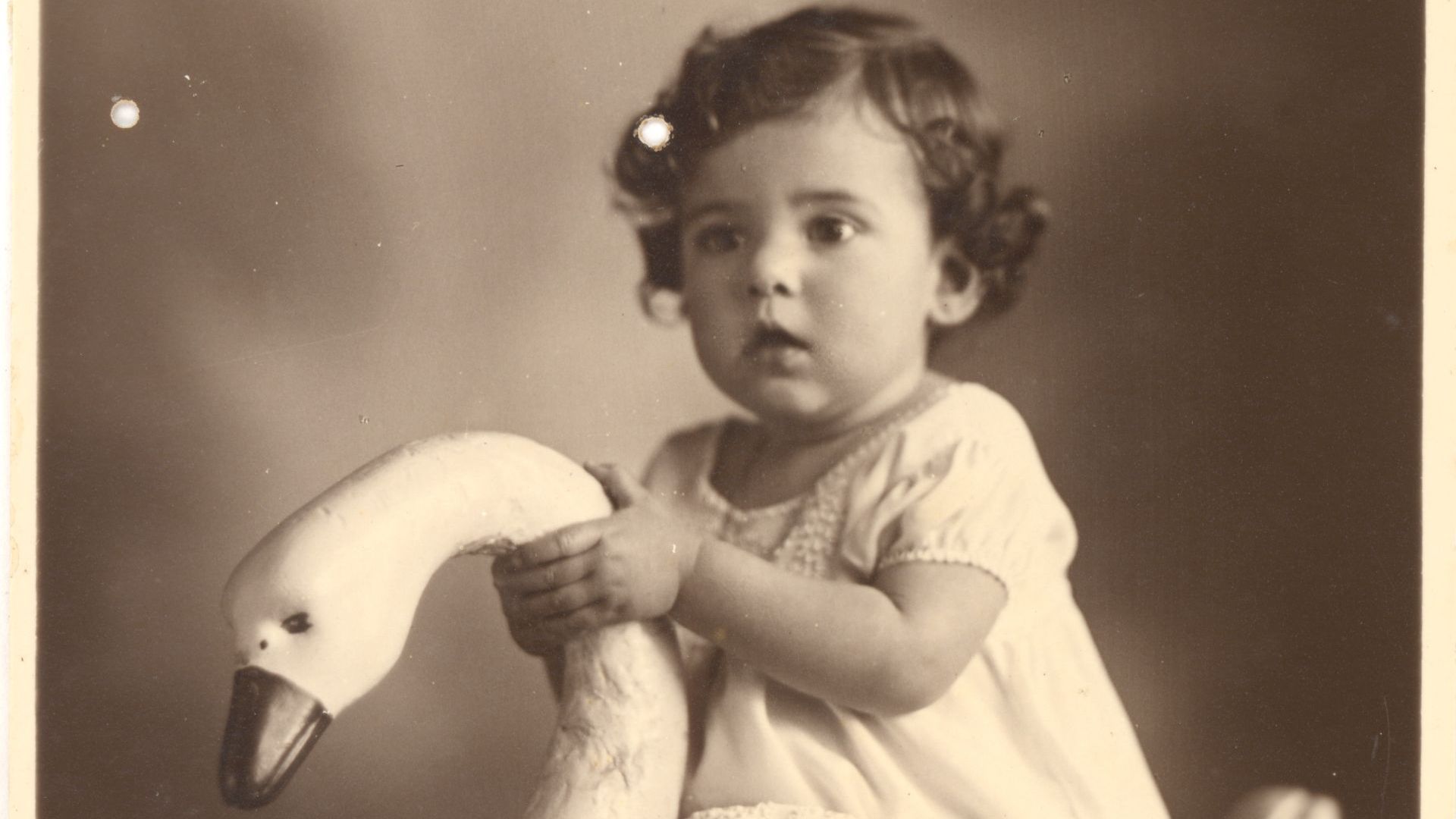 Ruth Rocha é criança e está em cima de um cisne de brinquedo