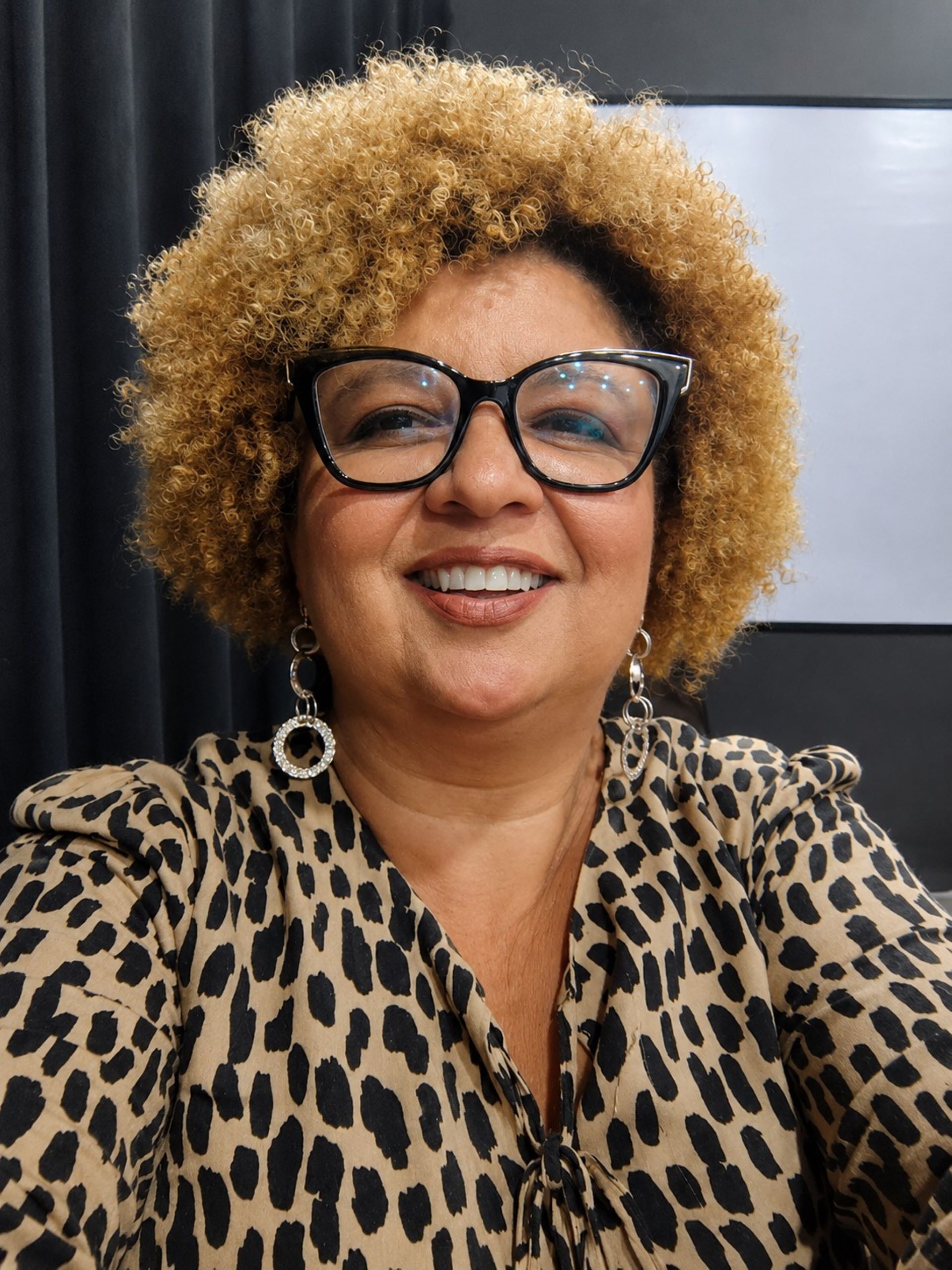 Adriana Medeiros usa óculos e blusa imitando pele de onça
