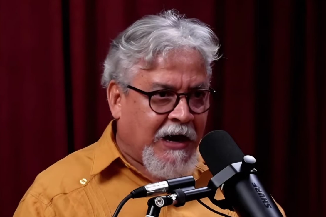 Foto do Edmilson Costa falando em um microfone de um PodCast