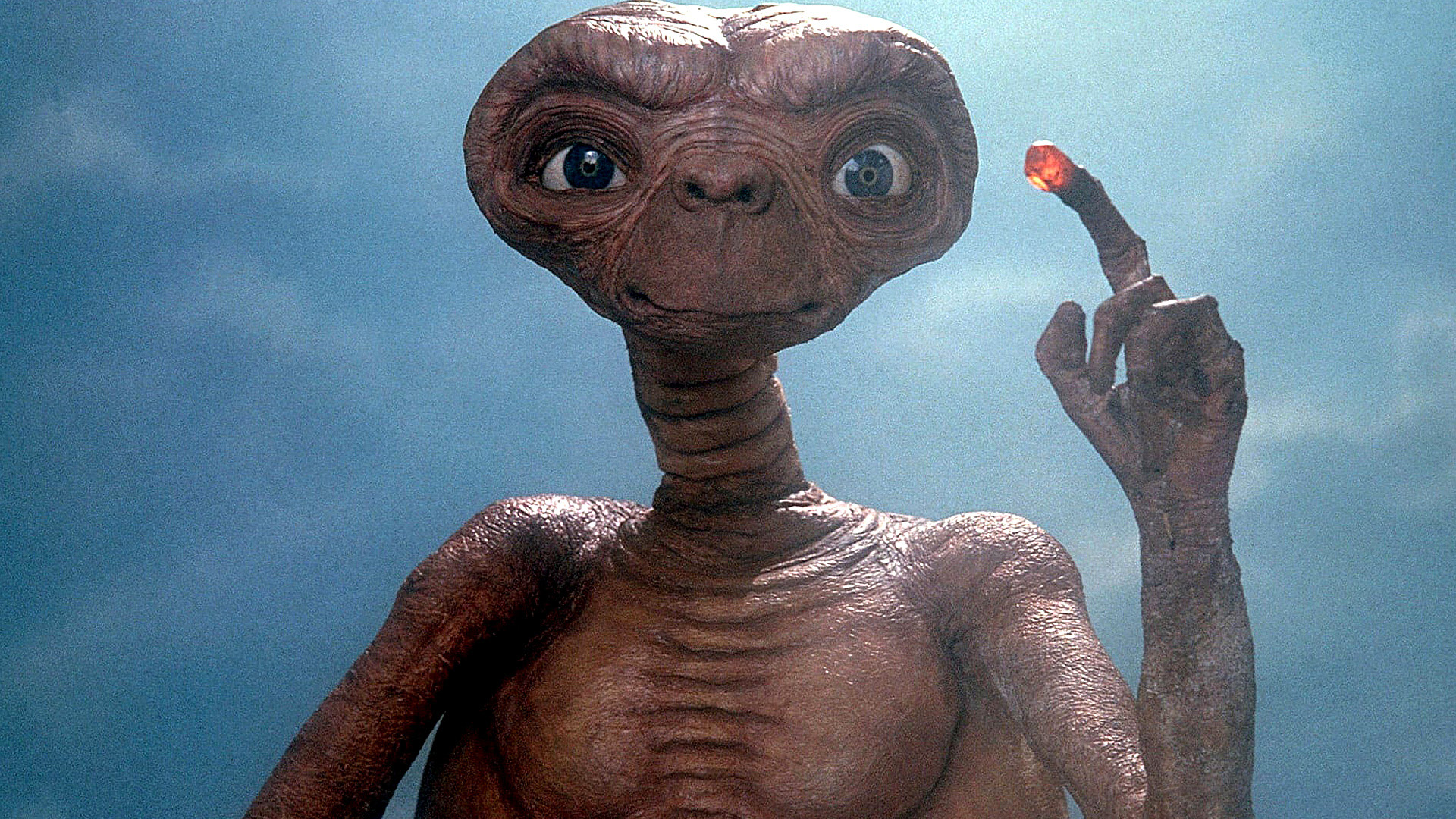 O personagem ET está com o dedo levantado, com luz acesa na ponta