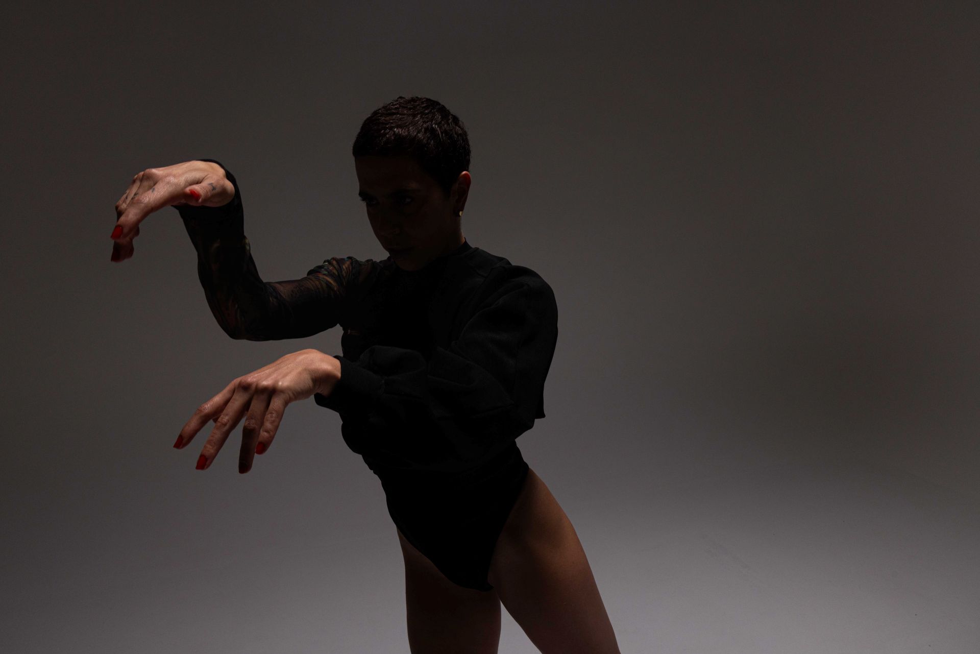 A bailarina Rafaela Sahyoun está com os dois braços levantados, na altura do seu corpo, dançando