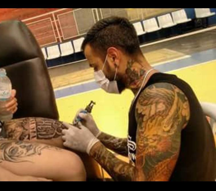 Tatuador Thiago Rodrigues fazendo tatuagem na perna de uma pessoa