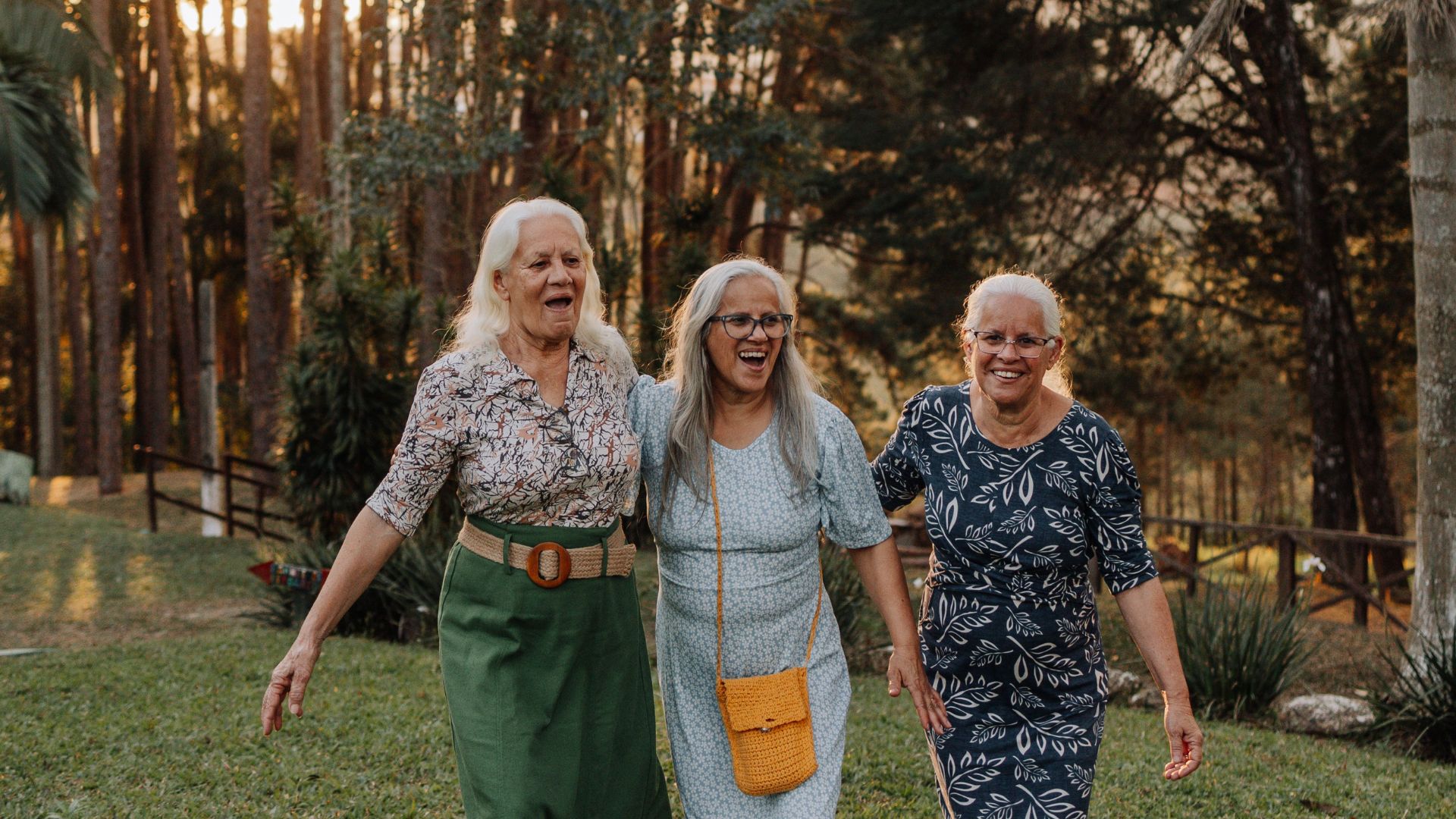 Três senhoras idosas caminhando juntas em um belo cenário ao ar livre no Brasil, demonstrando alegria e companheirismo.