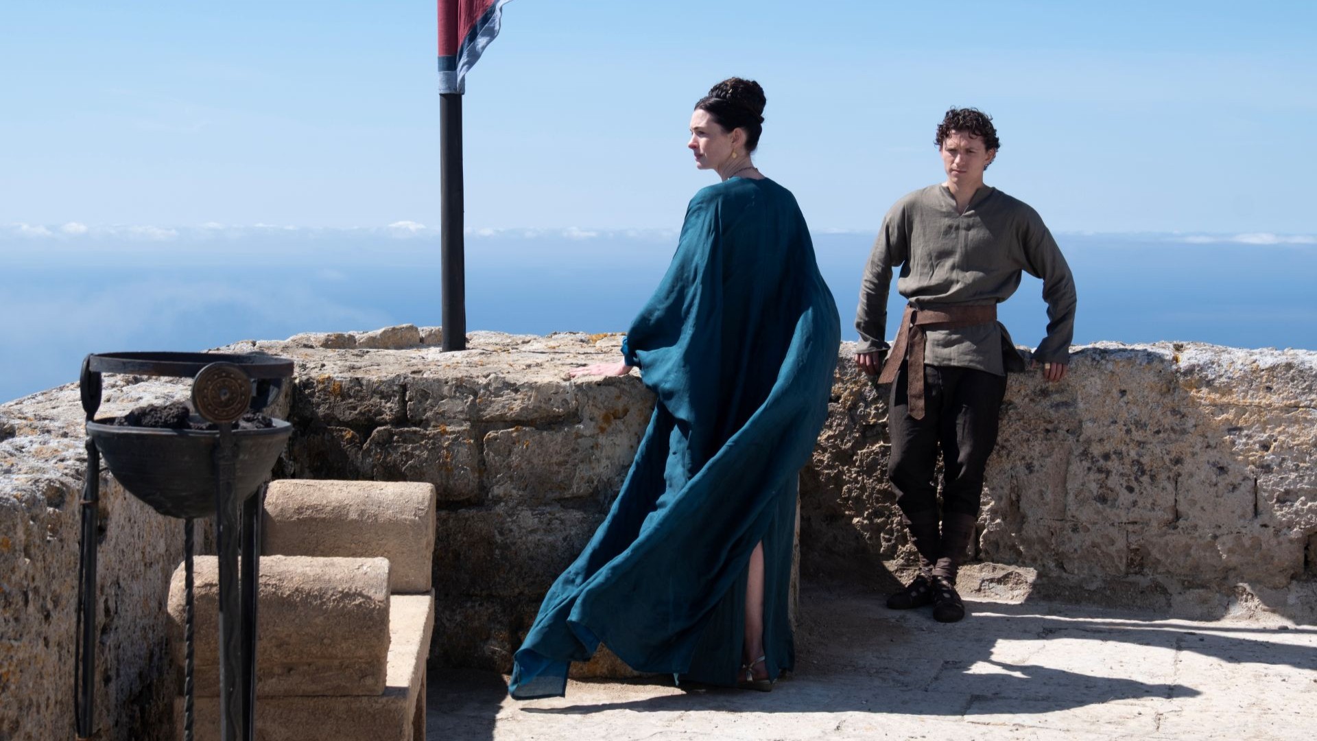 Anne Hathaway usa uma túnica azul e está de costas, ao lado de Tom Holland