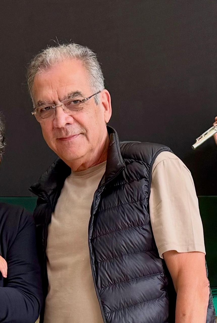 Carlos Torggler , de óculos, usa um colete escuro sobre camiseta bege