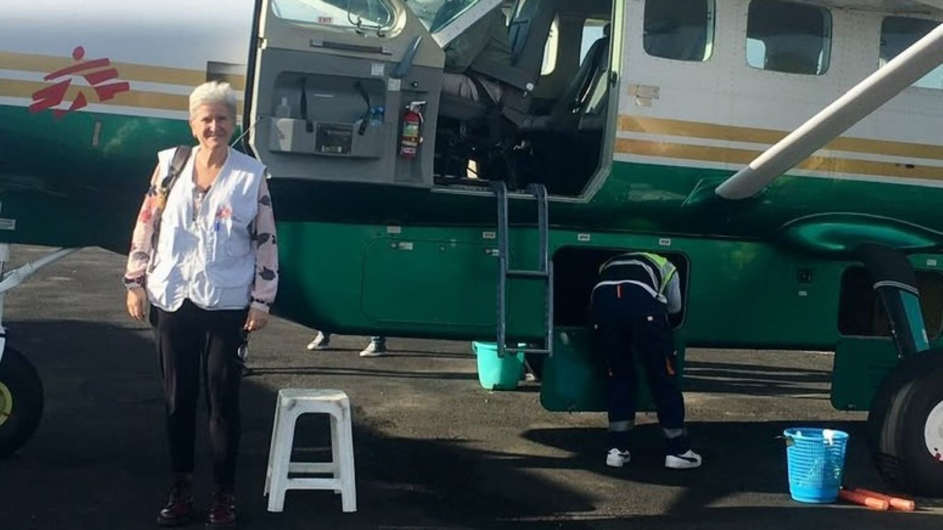 Denise Viuniski parada em frente de um avião da MSF com a porta aberta