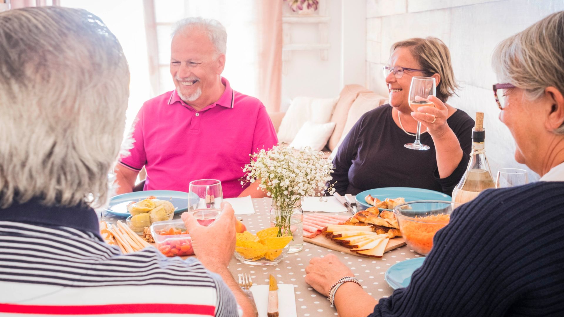 idosos reunidos em uma mesa enquanto comem e bebem vinho